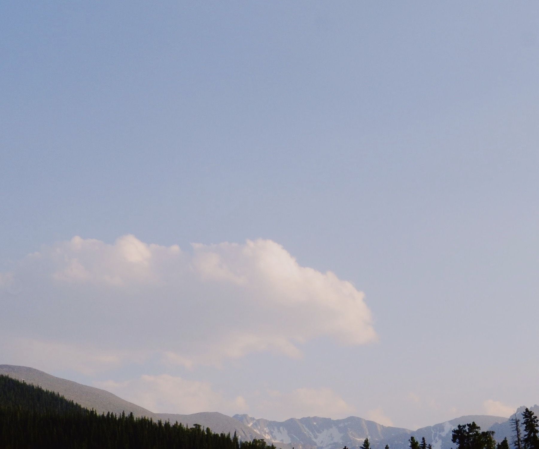A cloud over a forested ridge